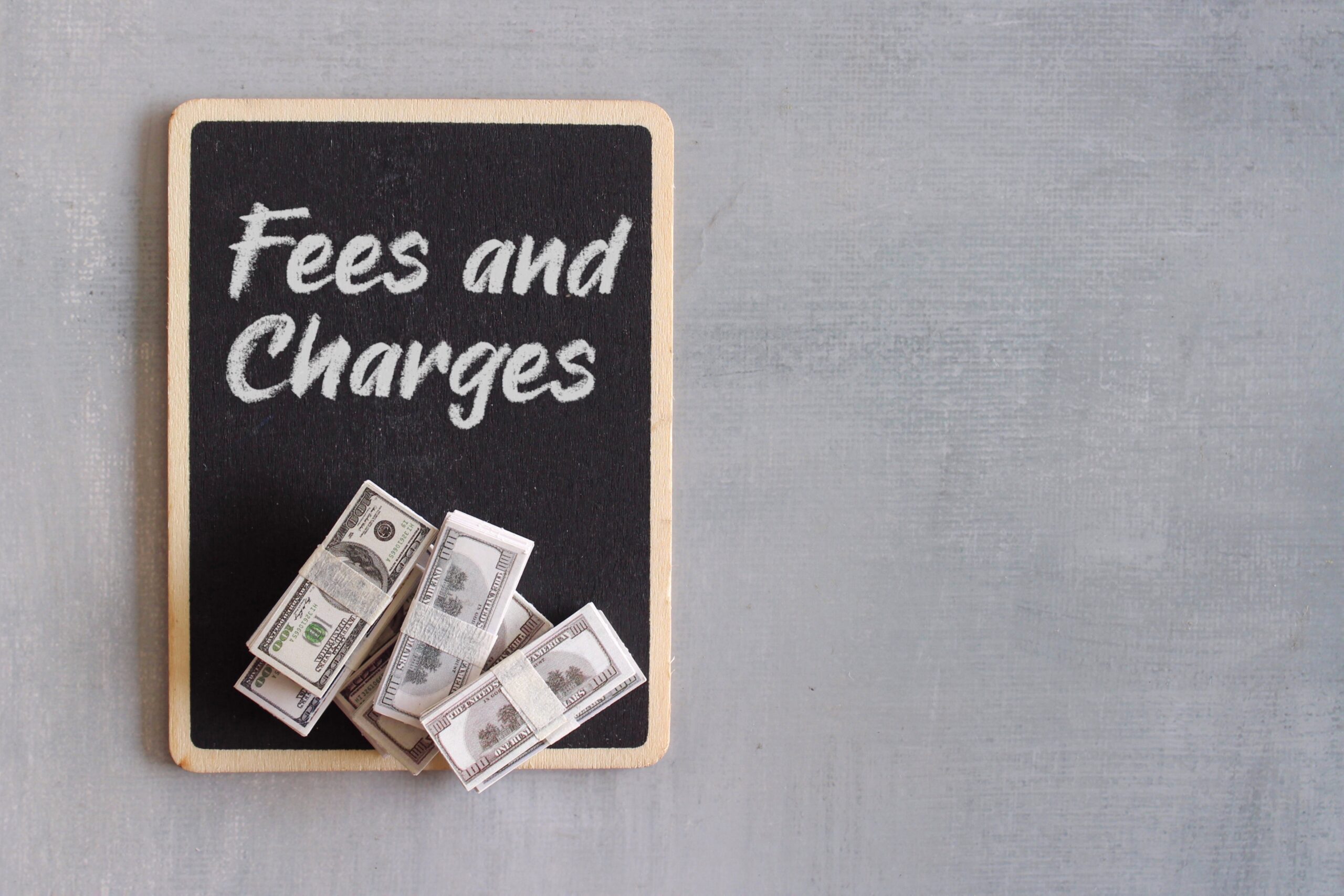 Top view image of money and chalkboard with text FEES AND CHARGES, Business and finance concept