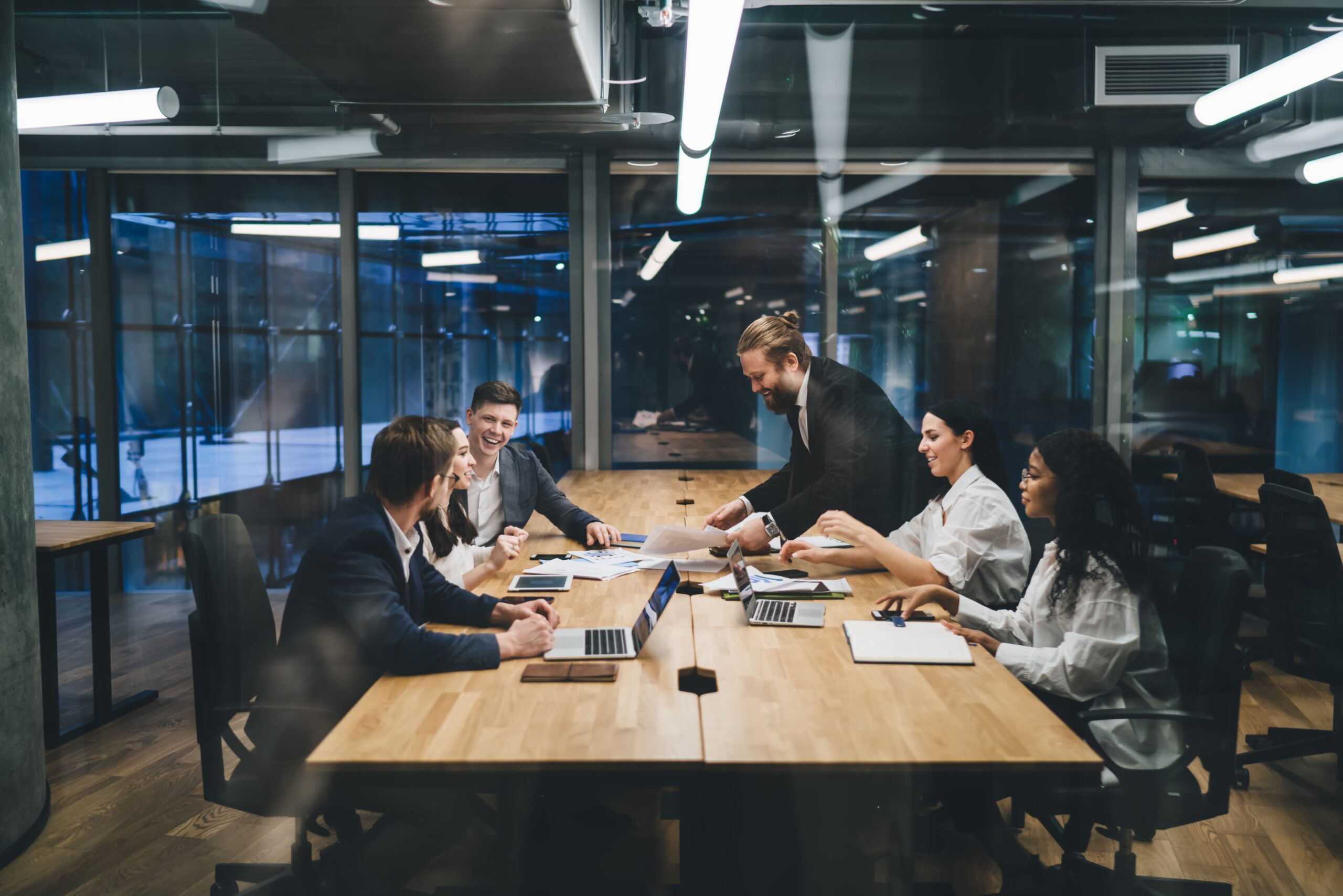 Team of colleagues laughing and collaborating on a project in a modern office conference room