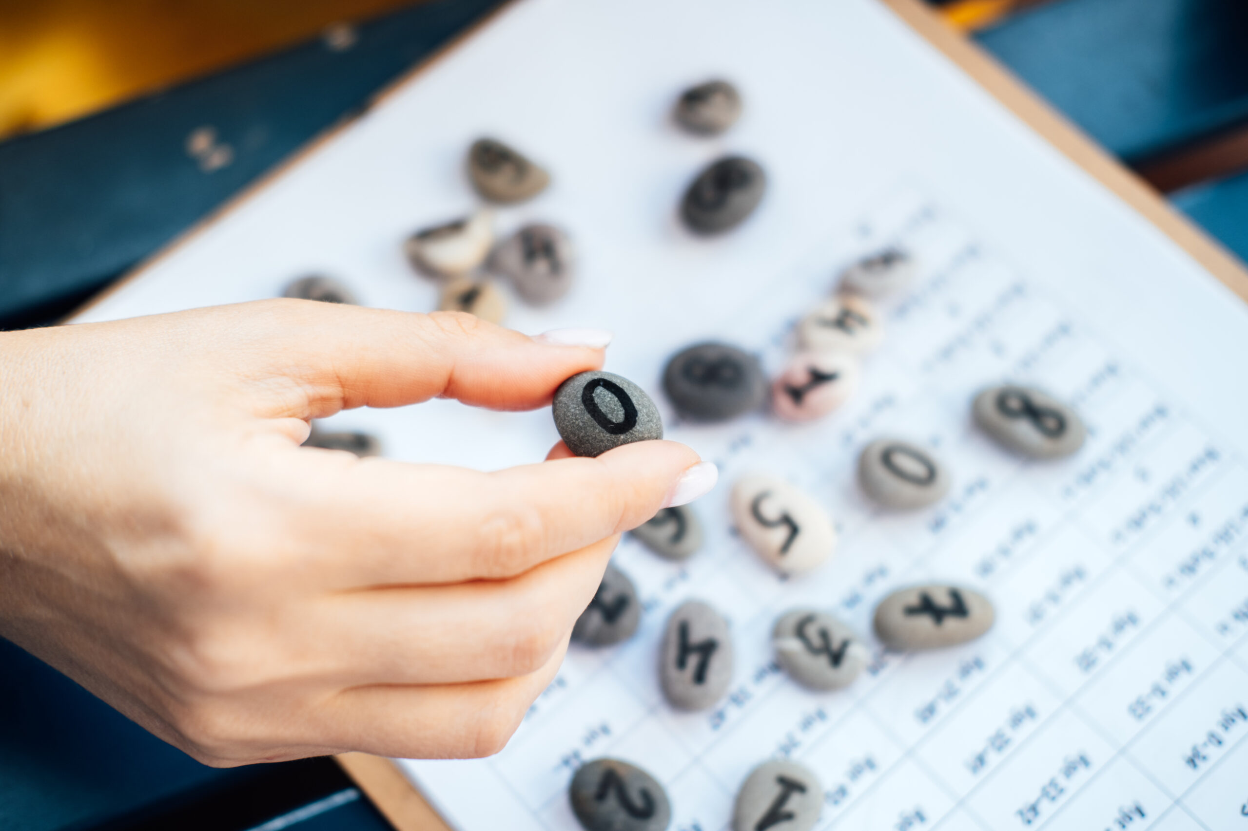 Woman numerologist hand with pebble stone with the number zero 0. Numerology Numbers Concept. Numerology Calculate Life Path and Destiny Numbers. Selective focus